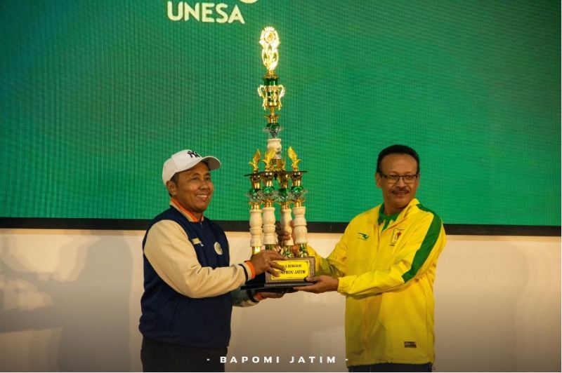 Ketua Bapomi Jatim, Martadi menyerahkan trofi juara umum Pomprov III Jatim 2025 kepada Unesa, yang diterima Wakil Rektor IV Unesa, Dwi Cahyo Kartiko.